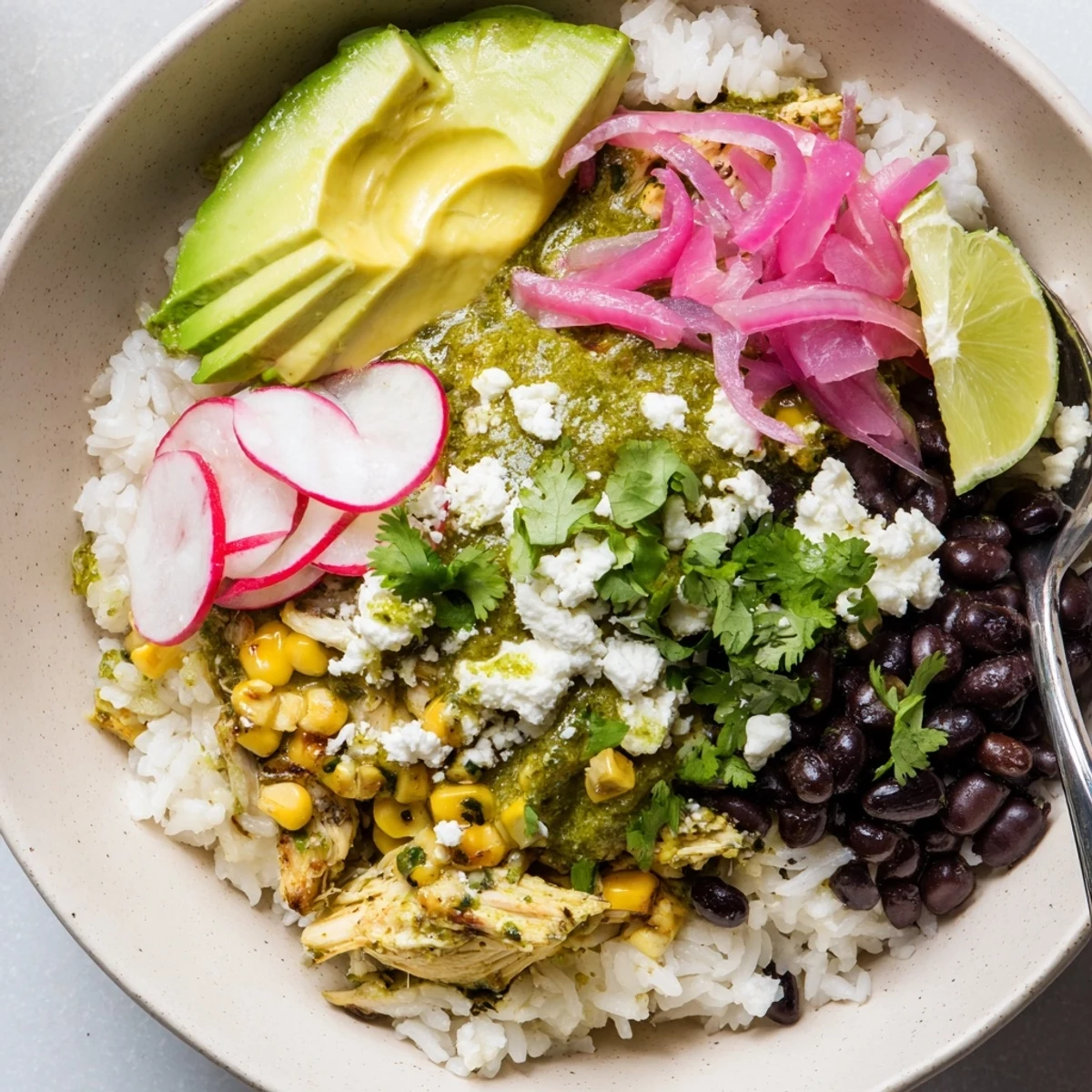 Zesty green enchiladas rice bowl garnished with crumbled cheese and sliced radishes.  