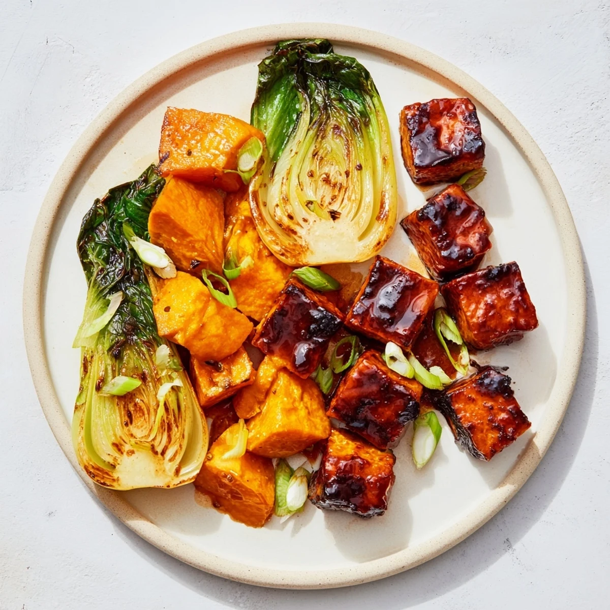Golden brown miso-glazed tofu and squash with vibrant bok choy plated for serving.