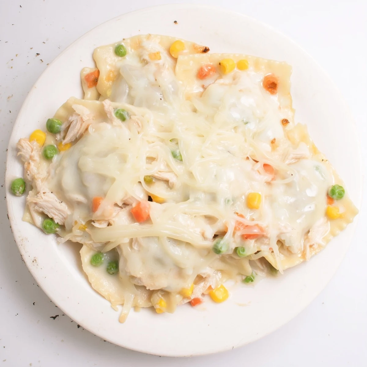 A close-up of a Chicken Pot Pie Ravioli Bake, showing the creamy filling and tender ravioli.