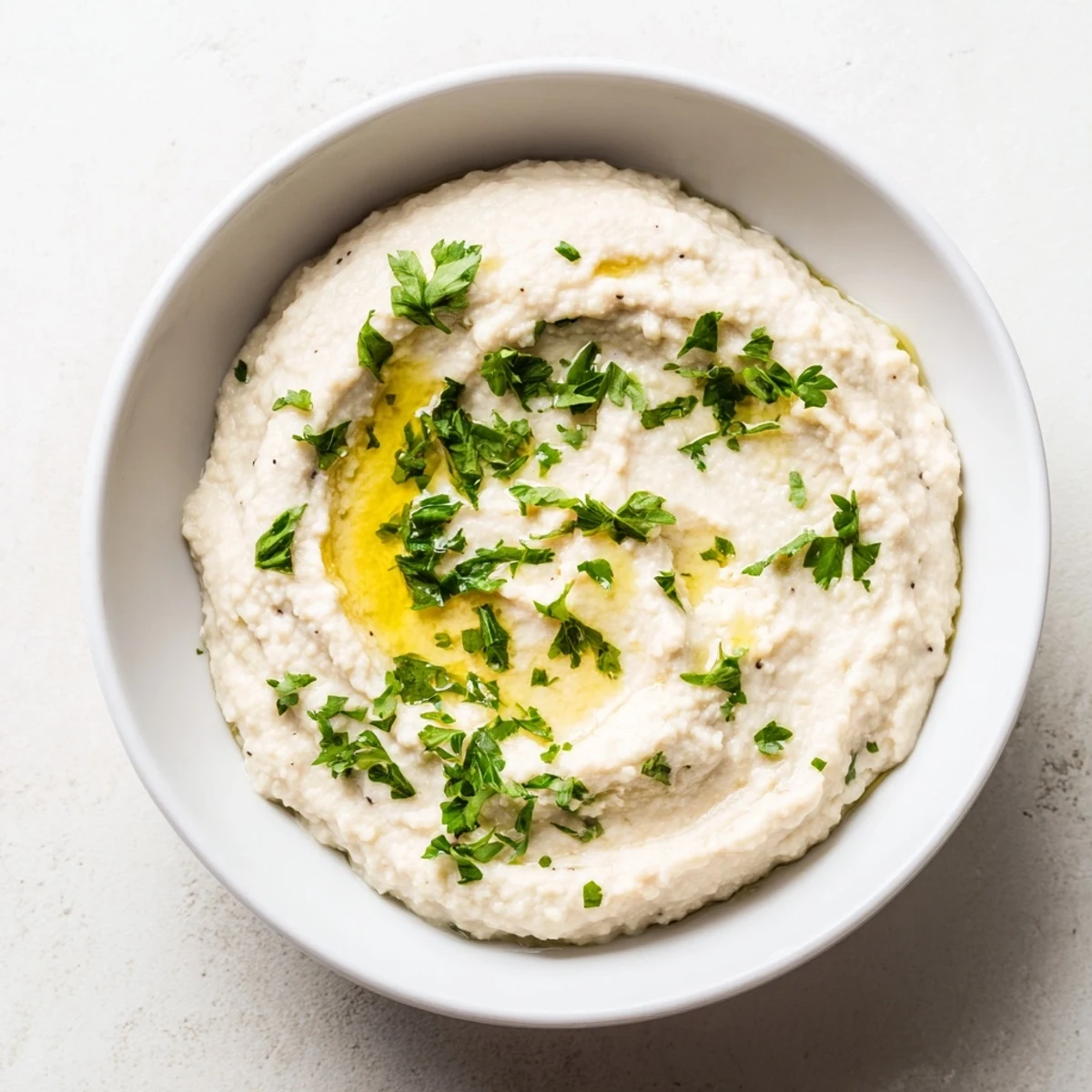 Creamy White Bean Dip, swirled with olive oil, ready to be scooped with warm pita bread.