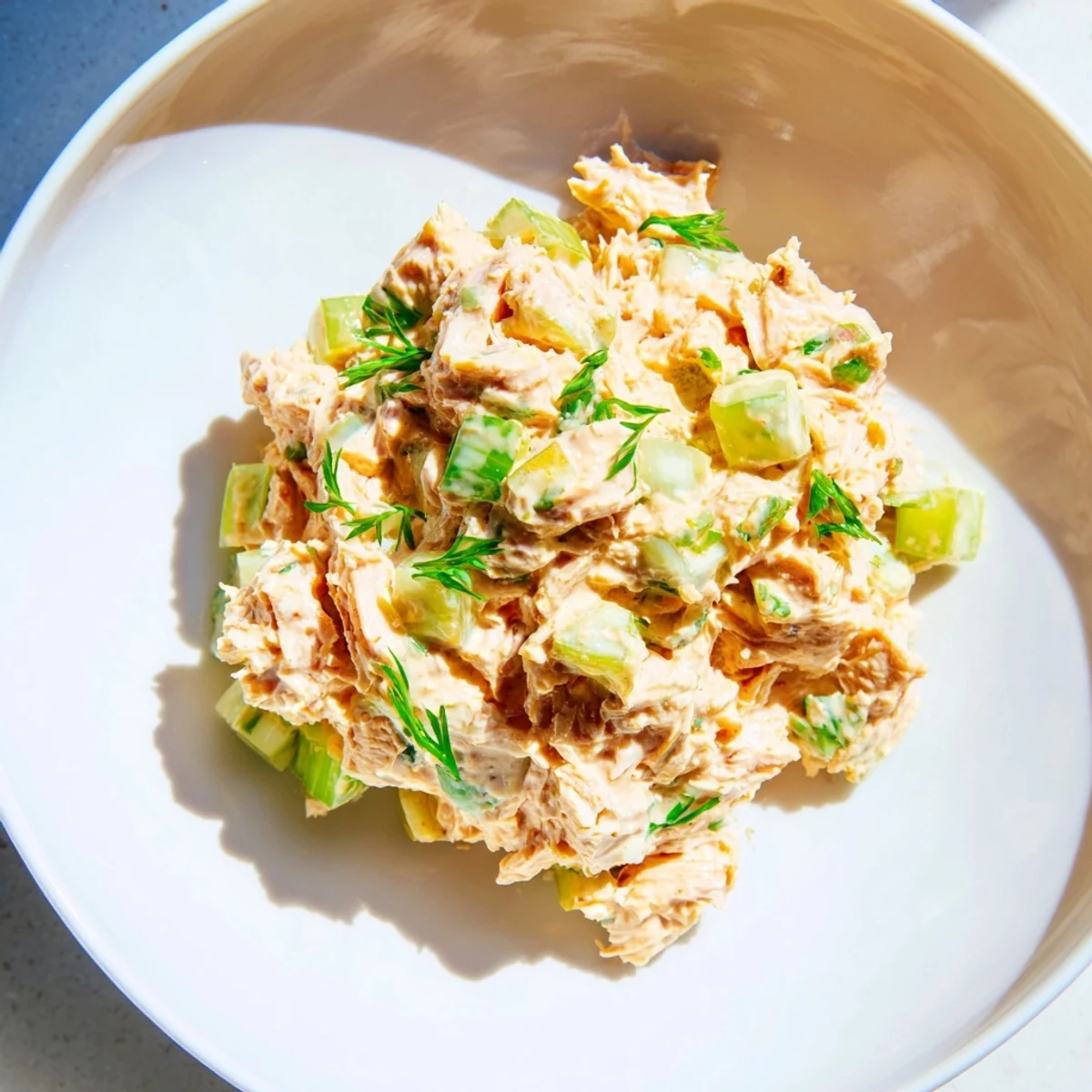 A close-up of Spicy Zesty Tuna Salad garnished with fresh parsley and lemon wedges on a rustic plate.