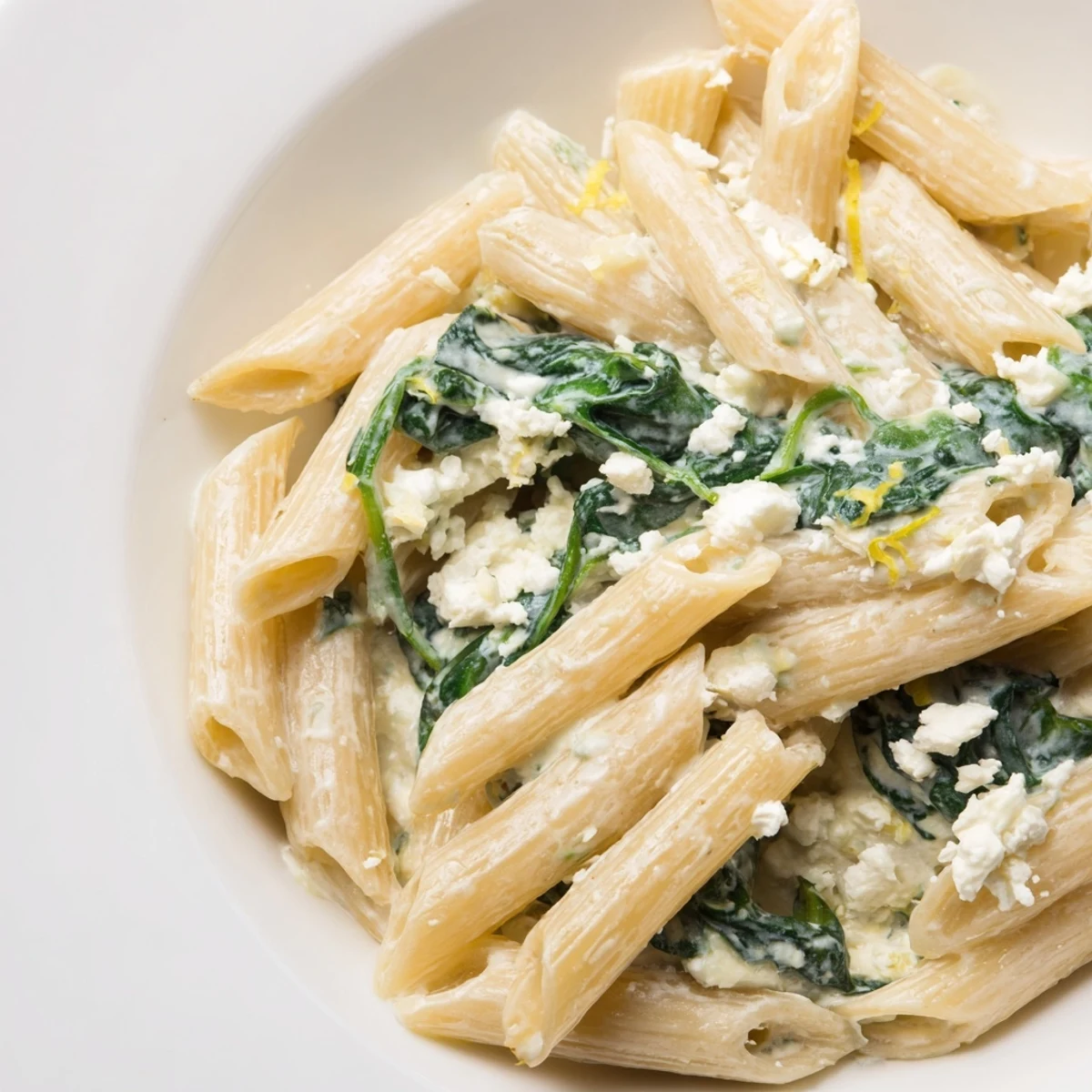 Creamy Feta Spinach Pasta served in a skillet with wilted spinach and crumbled feta cheese.