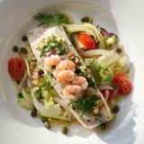 Golden blue fish fillets in Plongeons dans lOcéan Poisson Bleu, served with lemon wedges and fresh parsley.