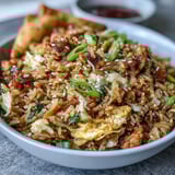A close-up of Crispy Chicken Fried Rice with Egg Roll Flavors shows fluffy rice, scrambled eggs, and toasted sesame seeds, ready to serve.