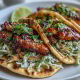Freshly warmed garlic naan holds honey garlic chicken and colorful cabbage slaw for a fusion taco night.