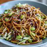 Fresh sesame ginger noodle bowl featuring chilled soba noodles, crunchy red cabbage, and a tangy ginger-tahini dressing.