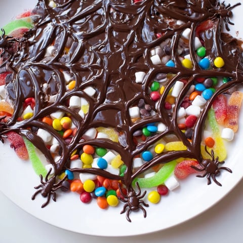 Dark chocolate spiderweb candy platter with colorful assorted candies and gummy spiders ready to eat.