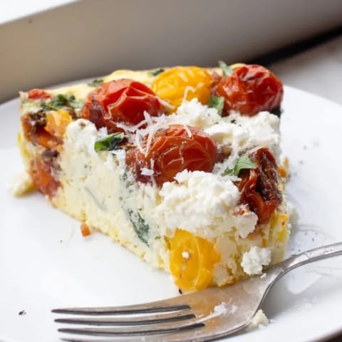 Warm Ricotta Tomato Basil Frittata with fresh herbs, ready to be sliced and enjoyed.