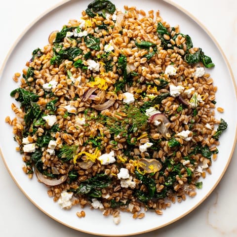 A steaming bowl of Warm Farro & Greens Pilaf, showing the fluffy farro and wilted greens.