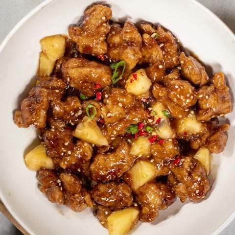 Golden-brown Brown Sugar Pineapple Chicken, ready to serve over rice, with a glistening, flavorful sauce.