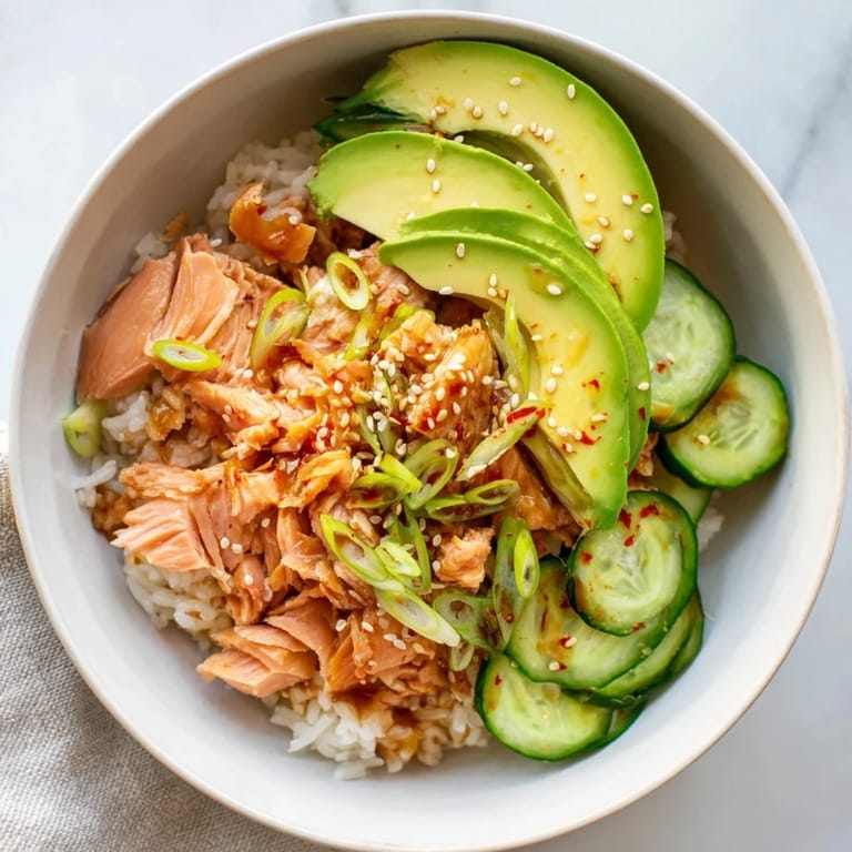 Quick leftover salmon & rice bowl brightly garnished with cucumber and sesame seeds.  