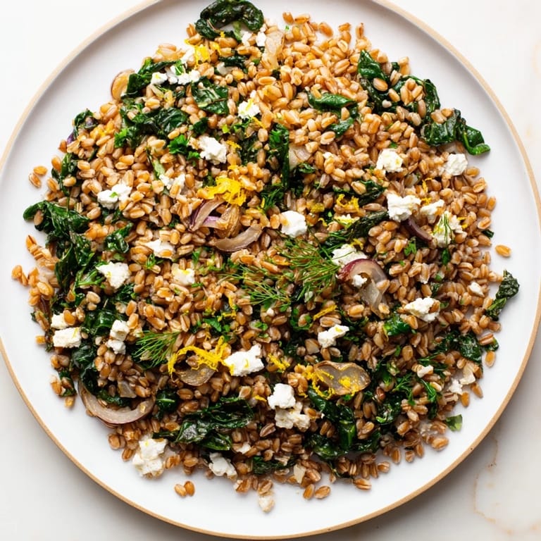 A steaming bowl of Warm Farro & Greens Pilaf, showing the fluffy farro and wilted greens.