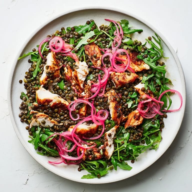 Freshly tossed Lentil & Chicken Spring Salad in a white bowl, with pickled red onions, cherry tomatoes, and a light vinaigrette glazing the greens.