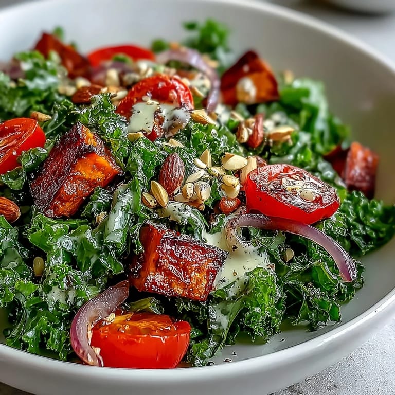 A hearty Kale Salad Bowl featuring golden roasted sweet potato and red bell pepper, tossed with pumpkin seeds and a zesty lemon tahini sauce.